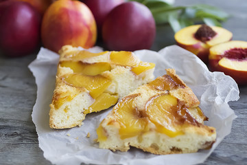 A pie with nectarines on a gray wooden table.