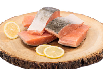 Frozen salmon fish fillets with lemon slices isolated on wood board.