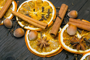 Christmas background: dried orange, cinamon, hazelnut, anise and cloves on dark brown wooden plank, copy space