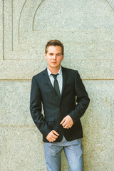 Portrait of Businessman. Dressing in black suit, tie, gray pants, a young professional standing against vintage style of wall, looking at you, confident, believing and success. ..