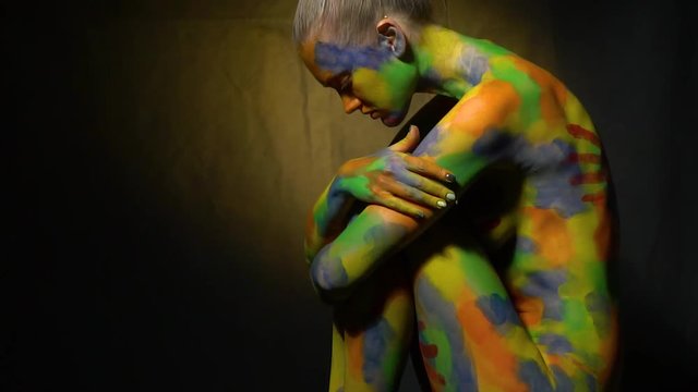 Nude blonde in body art sits on a chair