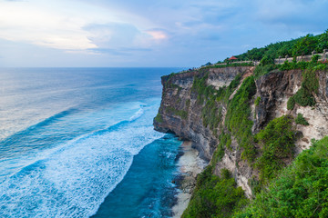 Beautiful view of Uluwatu temple and ocean rocky cliff on sunset. Scenic landscape of fantastic view. Bali, Indonesia.