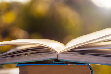 Open book on wooden table on natural background. Soft focus