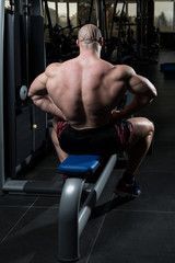 Fototapeta na wymiar Serious Bodybuilder Sitting In The Gym