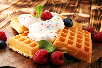 Plate of belgian waffles with whipped cream, mint and fresh berries