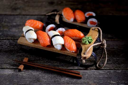 Sushi nigiri and rolls with salmon and fried squid on decorative sleigh, christmas background.