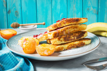 Cottage cheese pancakes with oats, syrniki and peach on concrete background