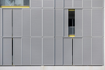 Modern gray facade of urban building with sun protect sliding metal panels on windows