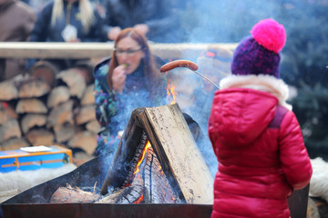 Dziewczynka piecze kiełbasę przy ognisku z mamą. - obrazy, fototapety, plakaty