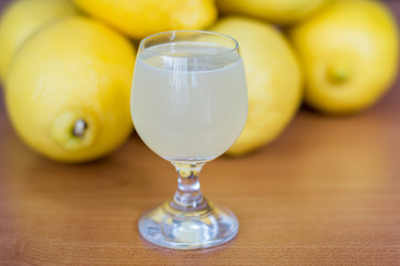 Lemon juice in glass with lemons in background.