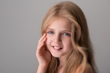 Young and beautiful. Portrait of joyful pretty little girl with long hair and naked shoulders is...