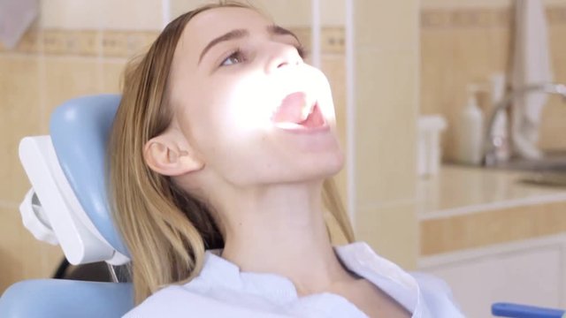 The girl in dentist's chair adjusts light herself