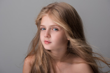 Naklejka premium Lovely pretty girl is looking at camera pensively while enjoying wind in her long hair. Isolated background