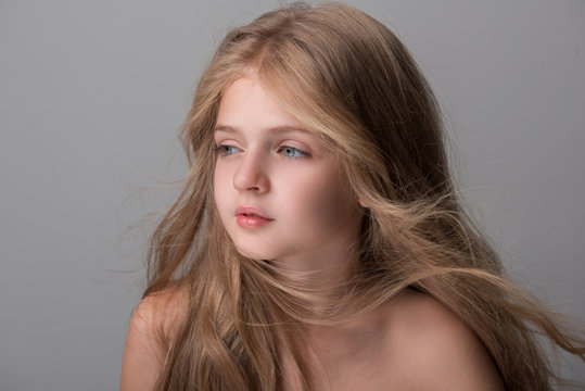 Sweet little girl with long hair is looking aside dreamily. Isolated background