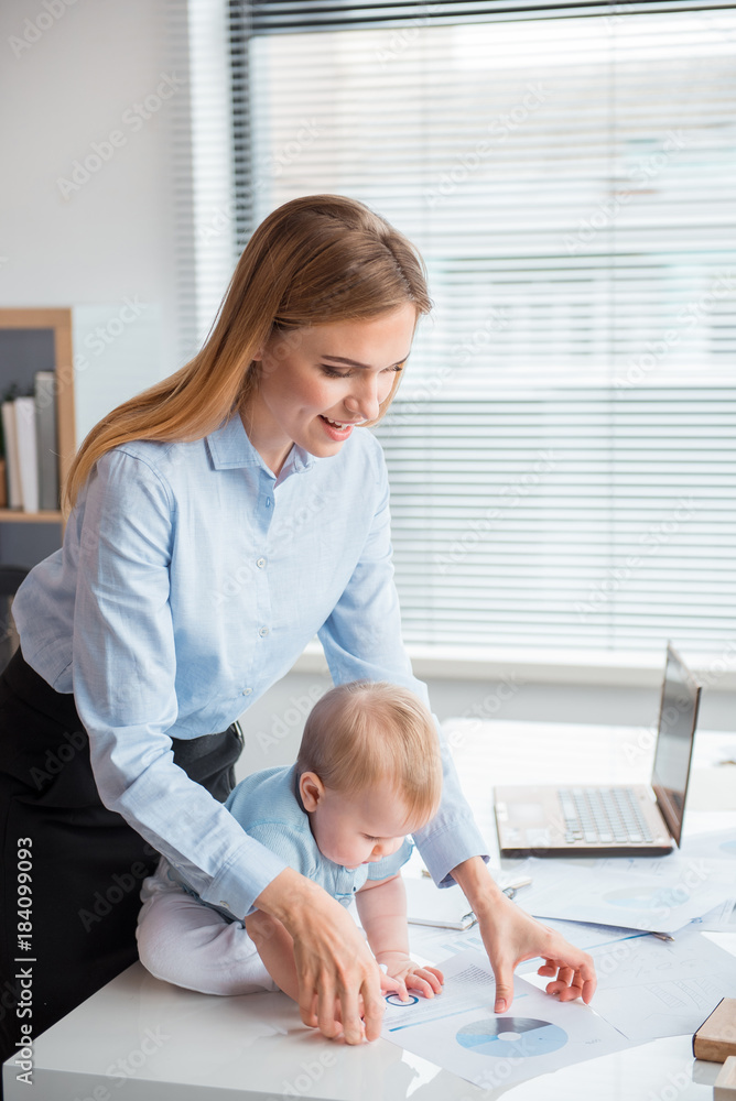 Poster side view happy mother showing document to intrigued kid. he locating on desk in room. labor and par