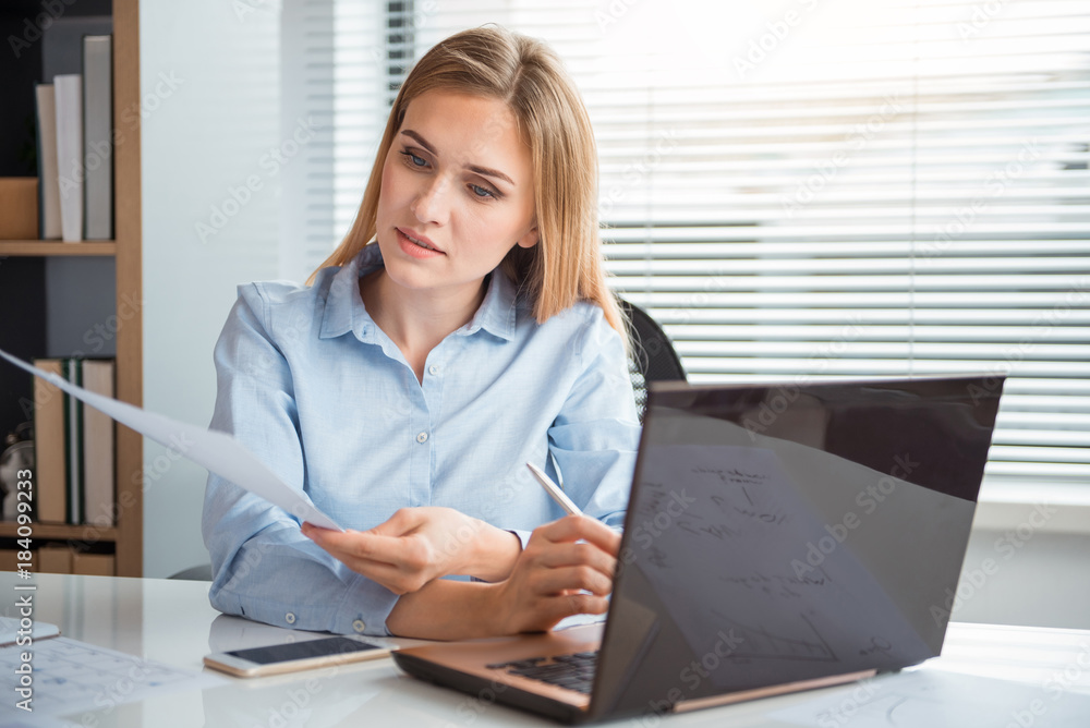 Poster portrait of serene career girl reading document while working on notebook computer. occupation conce