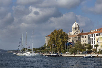 Fototapeta na wymiar Sibenik in Croatia, seaside of town with colorful stone houses and sailing boats and dome of Cathedral of St. James