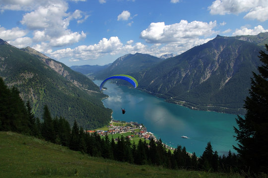 Paraglider hovers over a beautiful mountain lake in Austria.