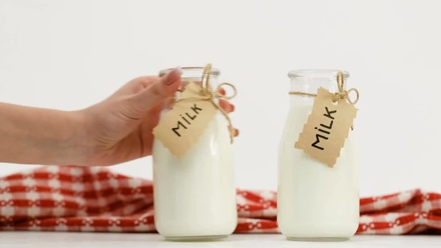 fresh milk assortment at markets. Woman hand puts three bottles in a row on white background