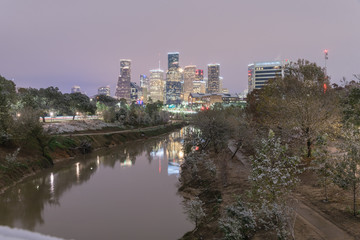 Fototapeta premium Unusual snowfall along Bayou River bank with downtown Houston, Texas, USA skylines city lights reflection at sunrise/twilight. Snow is extremely rarely in Houston and happen only 35 times since 1895