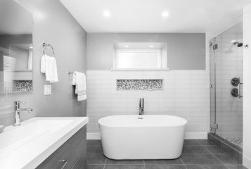 Obraz na płótnie Canvas Luxury bathroom interior with an oval bathtub black stone tiles and with glass shower in black and white