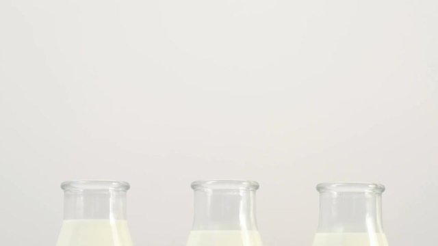 three milk bottles on white background without tags. Slide shot from bottom up. Free space concept