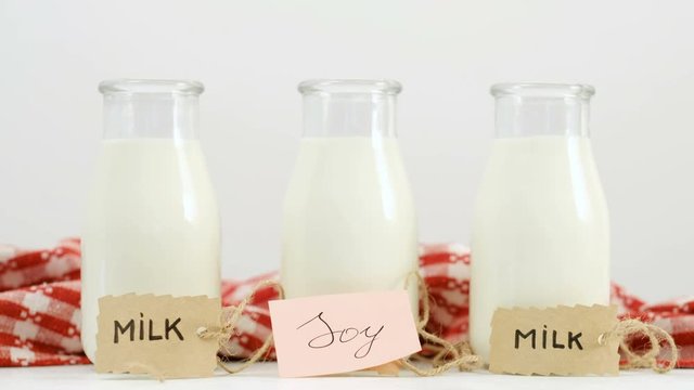 Different milk types. Soy versus cow milk. Healthy eating and vegan diet. Man hand putting a tag in front of a bottle
