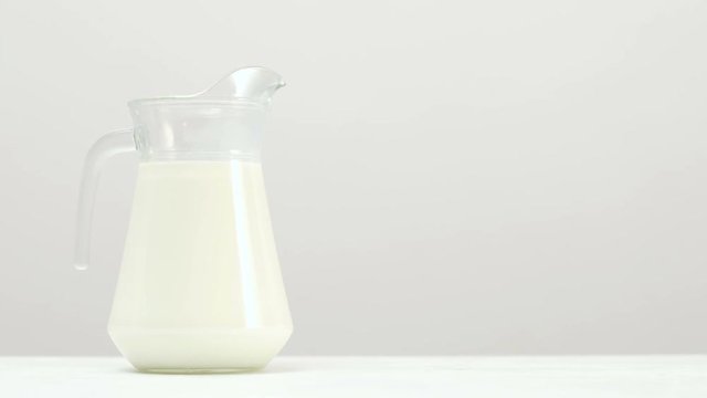 A slide shot of a glass jar full of milk on white background Organic dairy. Free space concept