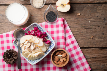 Bowl of oatmeal porridge with bananas, apple, dragon fruit and almonds. Top view