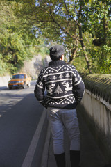 A fashionable man standing by the roadside, beside a wall of ancient Chinese sty