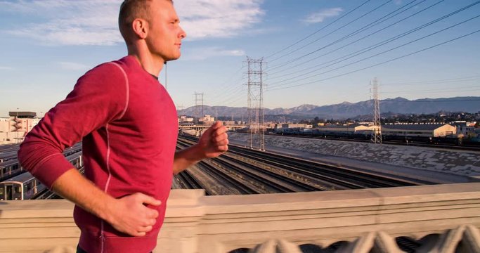 Athletic Male jogging across a bridge over the LA River, in an industrial area of Los Angeles. Slow Motion.