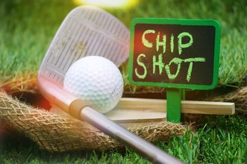 Chip shot with iron and golf ball on green grass
