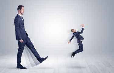 Giant businessman kicking out little businessman