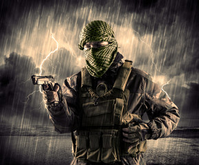 Dangerous armed terrorist with mask and gun in a thunderstorm with lightning