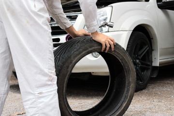 Obraz premium Selective focus on hands of professional mechanic in uniform holding wrench and tire at the repair garage background. Insurance car concept.
