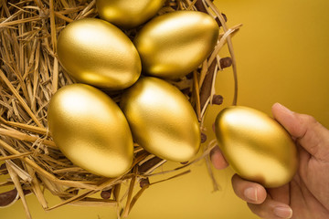 Financial success. Man holding a golden egg. Golden Egg on golden background