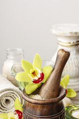 Wooden mortar with sea salt and orchid flower.