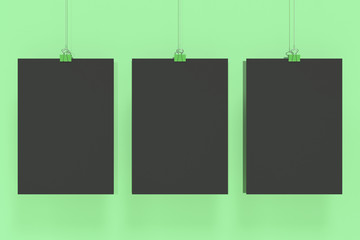 Three blank black posters with binder clip mockup on green background