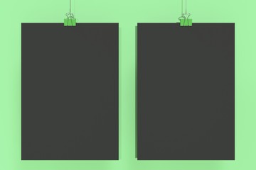 Two blank black posters with binder clip mockup on green background