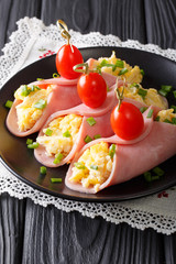 Festive snack: roll ham stuffed with scrambled eggs and tomatoes close-up. Vertical