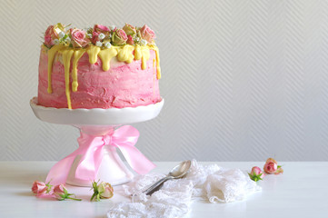 festliche rosa Erdbeer-Buttercreme-Torte mit gelb eingefärbtem Zuckerguss und mit Rosen und Schleierkraut dekoriert