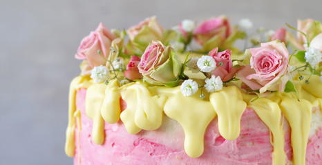 festliche rosa Erdbeer-Buttercreme-Torte mit gelb eingefärbtem Zuckerguss und mit Rosen und Schleierkraut dekoriert