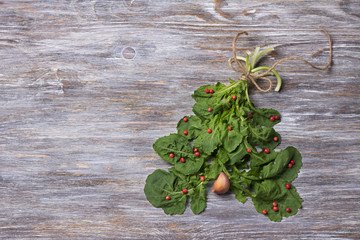 Christmas tree made from arugula with red pepper and garlic on a wooden surface with copy space, top view