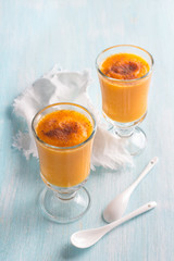 Fresh pumpkin smoothies with orange in glasses on a light blue background, selective focus