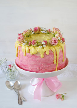 festliche rosa Erdbeer-Buttercreme-Torte mit gelb eingefärbtem Zuckerguss und mit Rosen und Schleierkraut dekoriert