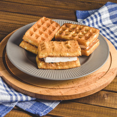 waffles with cream on plate on wooden table.