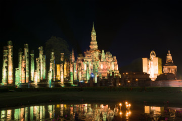 Fototapeta na wymiar Ruins of the temple of Wat Mahathat in the night illumination. Evening in the historical park of Sukhothai city. Thailand