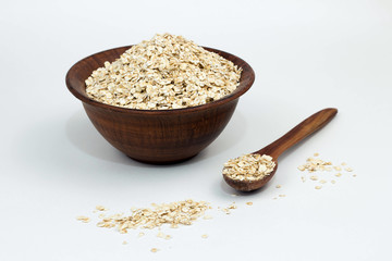 raw oat flakes in a clay plate on a white background