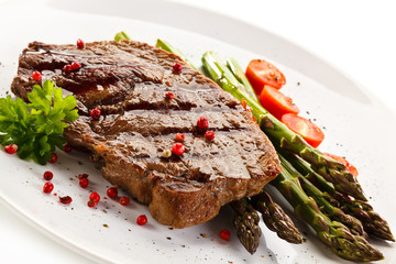 Grilled steak with asparagus on white background