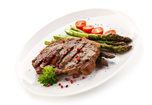 Grilled steak with asparagus on white background